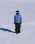 Model wearing Union.dsgn blue shell jacket and black shell pants standing on a snowy surface