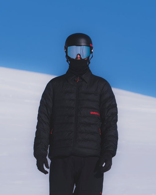 Model wearing a black primaloft jacket from Union.dsgn by the slopes in Gstaad